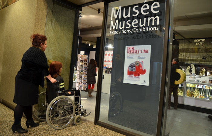 Personne en fauteuil roulant devant l'entrée du musée