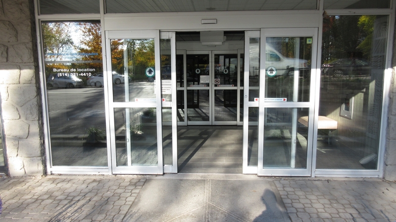 Porte d'entrée avec ouvre-porte automatique, trajet accessible vers la pharmacie