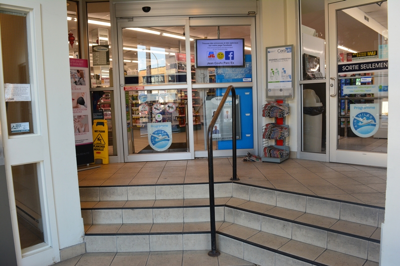 Vestibule d'entrée de la pharmacie, présence de marches et d'un ascenseur sur la droite
