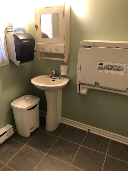 Salle de toilette équipée d'un lavabo accessible et d'une table à langer