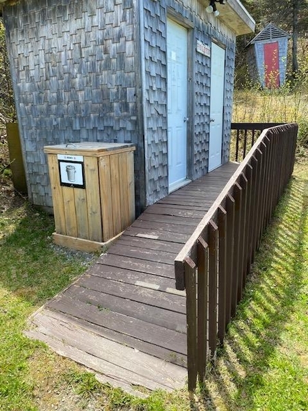 Rampe d'accès en bois menant aux salles de toilettes extérieures