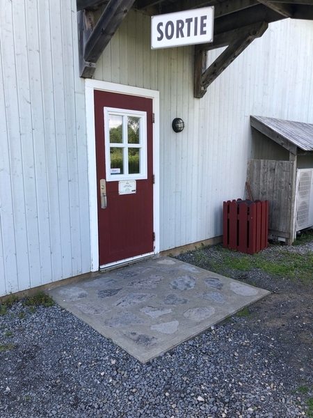 Porte de sortie située à l'arrière du bâtiment d'accueil présentant un seuil surélevé
